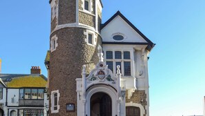 Un bâtiment historique doté d’une tour imposante, d’une grande entrée en arc de cercle et d’une façade de style traditionnel.