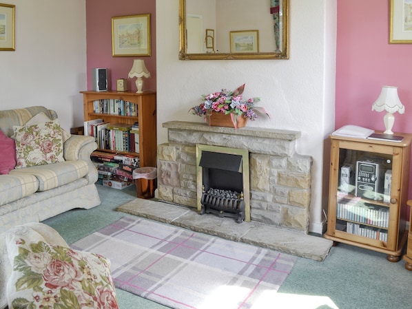A cozy living room with a fireplace, a sofa, a bookshelf, and a small side table.