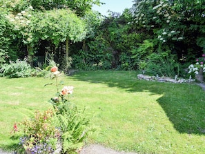 A well-maintained garden with a variety of plants and flowers, a stone pathway, and a grassy lawn.
