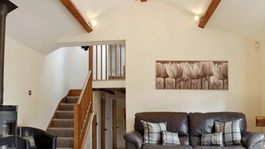 A living room with a brown leather sofa, a fireplace, a staircase, and a painting on the wall. - 3 bedroom accommodation in Kidderminster (Kidderminster)