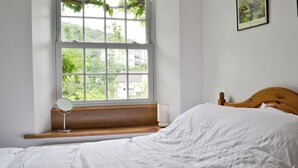 A bedroom with a large window, a wooden headboard, and a bedside table with a lamp. - 2 bedroom accommodation in Ambleside (Ambleside)