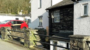 A stone building with a white exterior, a red car parked in front, and a stone fence. - 2 bedroom accommodation in Ambleside (Ambleside)