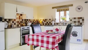 Une cuisine compacte comprenant une table à manger, des chaises, un lave-linge et une horloge murale.