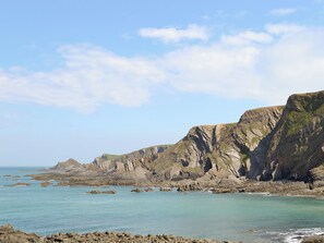A coastal landscape with rocky cliffs and calm sea.