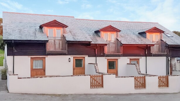 Une rangée de bâtiments blancs avec des balcons et des portes en bois.