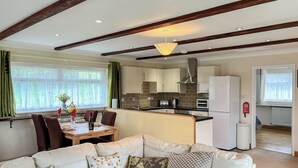 A modern living room with a sofa, a dining table, and a kitchen area with a refrigerator, oven, and sink. - 1 bedroom accommodation in East Taphouse, near Liskeard (East Taphouse, near Liskeard)
