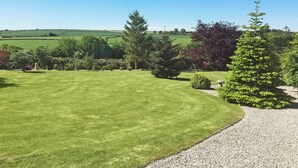 A well-maintained lawn with a gravel path, surrounded by various trees and shrubs, and a view of rolling green fields in the distance. - 1 bedroom accommodation in East Taphouse, near Liskeard (East Taphouse, near Liskeard)