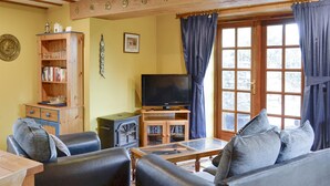 Un salon chaleureux avec une cheminée, un téléviseur et des fauteuils confortables.