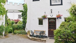 A white building with black trim, a wooden bench, and flower baskets. - 4 bedroom accommodation in Keswick (Keswick)