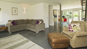 A modern living room with a sectional sofa, a small ottoman, and a dining area with a table and chairs. - 2 bedroom accommodation in Sutton Bridge, Spalding (Sutton Bridge, Spalding)