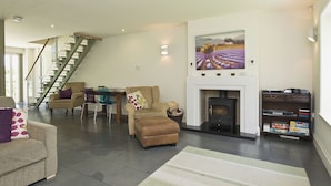 A spacious living area with a fireplace, a dining table, and a staircase. - 2 bedroom accommodation in Sutton Bridge, Spalding (Sutton Bridge, Spalding)