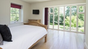A bedroom with a bed, a TV, a window, and a view of greenery. - 2 bedroom accommodation in Sutton Bridge, Spalding (Sutton Bridge, Spalding)