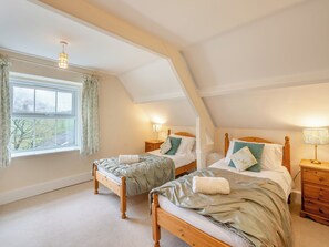 Une chambre avec deux lits, une fenêtre avec des rideaux et un plafond en pente.