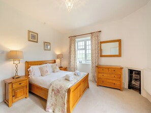 A bedroom with a wooden bed, nightstands, a dresser, a mirror, and a fireplace.