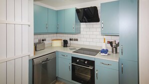 A compact kitchen with light blue cabinets, a built-in oven, a dishwasher, and a coffee maker. - 2 bedroom accommodation in Wells-next-the-Sea (Wells-next-the-Sea)