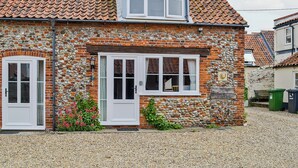 A stone house with a tiled roof, a small window, and a door. - 2 bedroom accommodation in Wells-next-the-Sea (Wells-next-the-Sea)