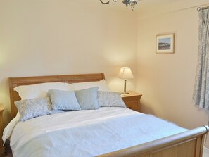 A neatly made bed with a wooden headboard, a bedside lamp, and a framed picture on the wall.