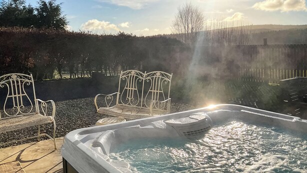 A hot tub with a view of a forested area and a bench. - Kielder Cottage Spa - E3533 (Kielder)