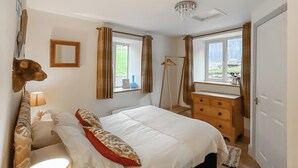 A bedroom with a bed, bedside table, lamp, dresser, and a mirror. - Kielder Cottage Spa - E3533 (Kielder)