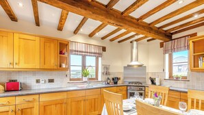 Cucina con mobili in legno, tavolo da pranzo per quattro persone e una grande finestra con vista all'esterno.