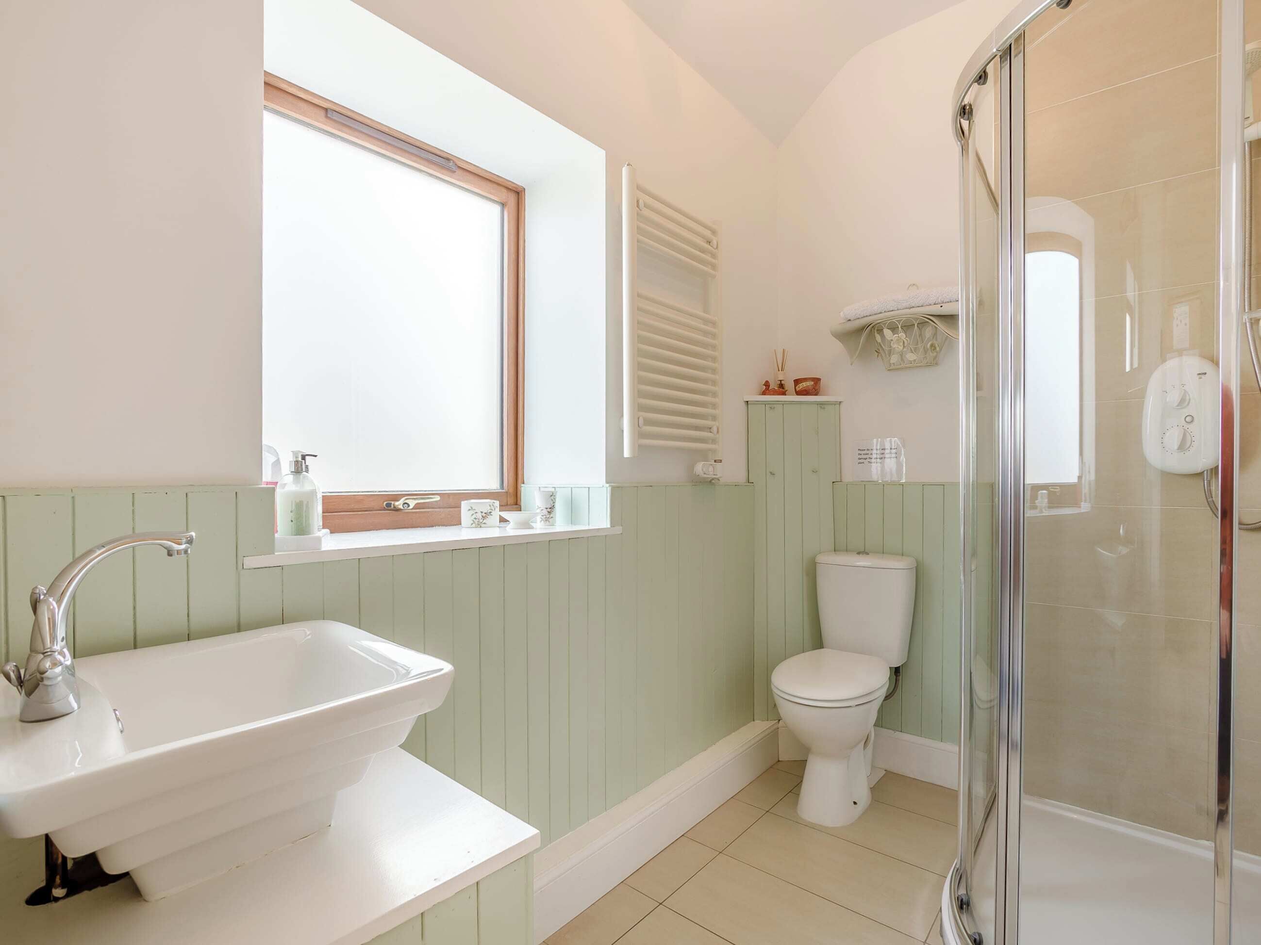 Een badkamer met een wit wastafelmeubel, toilet en een douchecabine.