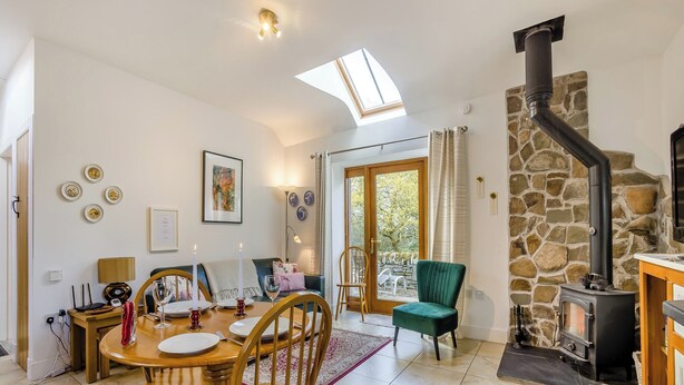 A cozy living room with a stone fireplace, a dining area with wooden furniture, and a skylight. - 1 bedroom accommodation in Tealing, near Dundee (Tealing, near Dundee)