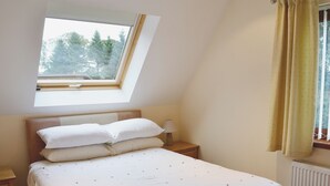 A bedroom with a skylight, a bed with white bedding, a nightstand, and a window with curtains. - 3 bedroom accommodation in Oakley, near Dunfermline (Oakley, near Dunfermline)
