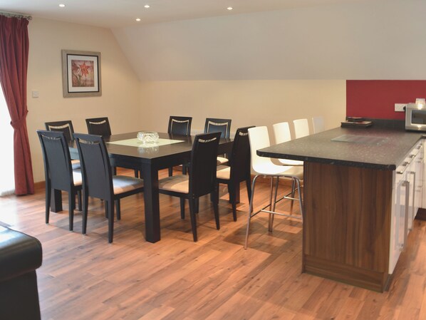 Un espace repas comprenant une table en bois, des chaises et un îlot de cuisine doté d’un plan de travail.