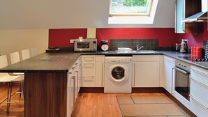 A compact kitchen with a built-in washing machine, a microwave, and a toaster. - 3 bedroom accommodation in Oakley, near Dunfermline (Oakley, near Dunfermline)