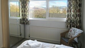 Een slaapkamer met een groot raam, een stoel en een bed.