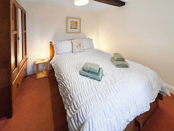 A neatly made bed with a white duvet and pillows, a bedside table with a lamp, and a framed picture on the wall. - 3 bedroom accommodation in Blawith, near Coniston (Blawith, near Coniston)