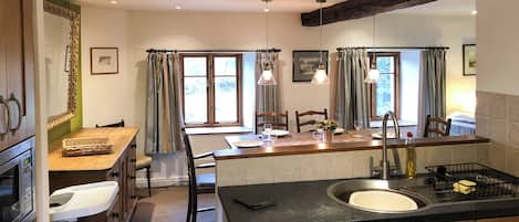 A compact kitchen with a central island, a sink, and a dining area with chairs and a table.