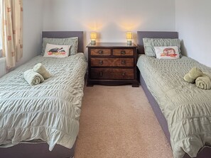 A twin bedroom with two beds, each with a pillow and a rolled towel. There is a wooden dresser between the beds with two lamps on top. - 3 bedroom accommodation in Blawith, near Coniston (Blawith, near Coniston)