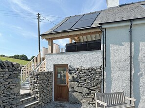 A two-story building with a stone facade, a wooden door, and a bench outside. - 3 bedroom accommodation in Blawith, near Coniston (Blawith, near Coniston)