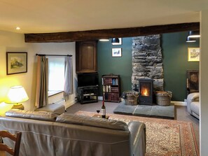 A cozy living room with a stone fireplace, leather sofa, and a bookshelf. - 3 bedroom accommodation in Blawith, near Coniston (Blawith, near Coniston)