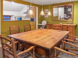 A dining area with a wooden table and chairs, a kitchen in the background, and a mirror on the wall. - 3 bedroom accommodation in Blawith, near Coniston (Blawith, near Coniston)