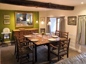 A dining room with a wooden table set for six, surrounded by chairs. A high-backed wooden chair is positioned at the head of the table. - 3 bedroom accommodation in Blawith, near Coniston (Blawith, near Coniston)