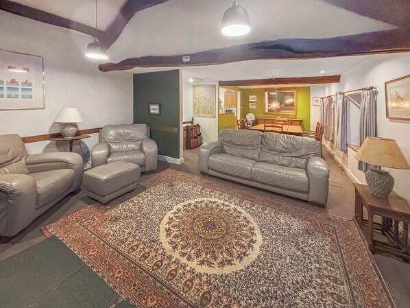 A living room with a patterned rug, leather sofas, and a dining area in the background. - 3 bedroom accommodation in Blawith, near Coniston (Blawith, near Coniston)