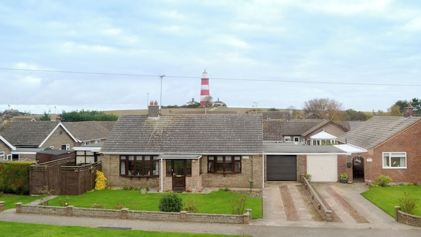 A residential area with houses, a red and white lighthouse, and a clear sky. - 5 bedroom accommodation in Happisburgh (Happisburgh)