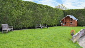 A grassy area with a wooden bench, a picnic table, and a wooden cabin with a sloped roof. - 5 bedroom accommodation in Happisburgh (Happisburgh)