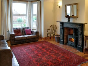 A living room with a fireplace, a sofa, a chair, and a patterned rug.
