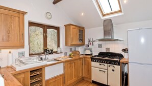 Una cocina con armarios de madera, estufa a gas, refrigerador blanco y tragaluz.