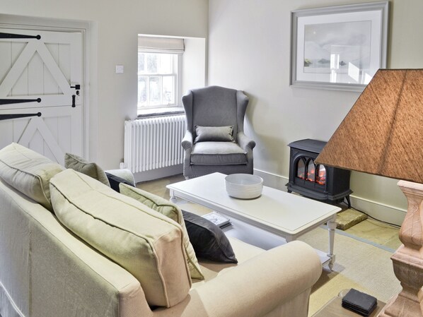 A living room with a sofa, armchair, coffee table, and a fireplace.