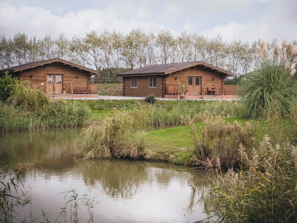 Eine Holzhütte mit Veranda und Teich davor.