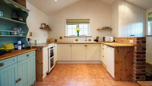 A kitchen with white cabinets, a wooden countertop, and a tiled floor.