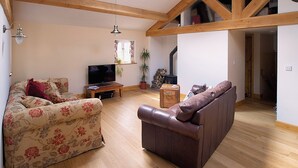 A living room with a sofa, a television, a wooden coffee table, and a potted plant.