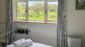 A bedroom with a window, a radiator, and a bed with a white duvet. - 2 bedroom accommodation in Shaftesbury (Shaftesbury)