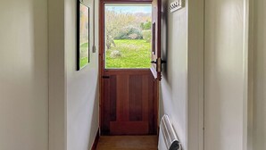 A narrow hallway with a wooden door leading to a garden. - 2 bedroom accommodation in Shaftesbury (Shaftesbury)