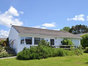 A single-story white building with a sloped roof, large windows, and a small porch area.