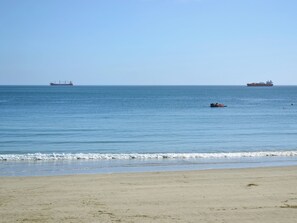 A beach with calm waters, a distant ship, and a clear sky. - 3 bedroom accommodation in Coverack, near Helston (Coverack, near Helston)